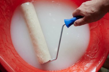 Yapay tüylü sentetik kumaştan yapılmış boya silindiri. Kırmızı bir leğen içinde tutkal var. Yapışkan yapıştırıcıyı yapıştırırken duvarlara ve duvar kağıdına yapıştırmak için kullanılır.