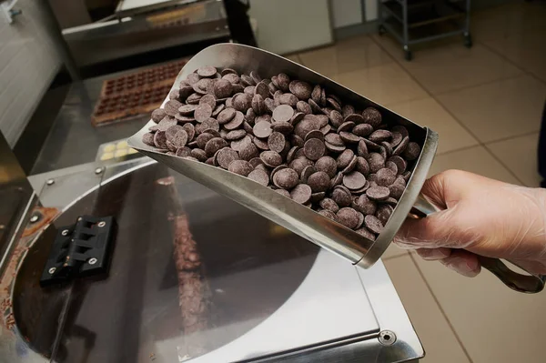 生菓子職人の手にチョコレートを入れたラドル生産ラインの背景にチョコレートの小規模な卸売生産 — ストック写真