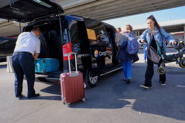 Antalya, Türkiye - 13 Kasım 2020: Valizli turistler, tekerlekli bavullar, havaalanının önündeki meydanda. Maskeler, salgın sırasında ve kısmi tecrit sırasında Akdeniz tatil beldesine geldi.