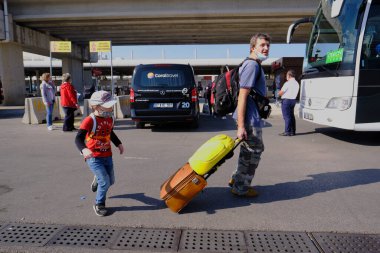 Antalya, Türkiye - 13 Kasım 2020: Valizli turistler, tekerlekli bavullar, havaalanının önündeki meydanda. Maskeler, salgın sırasında ve kısmi tecrit sırasında Akdeniz tatil beldesine geldi.