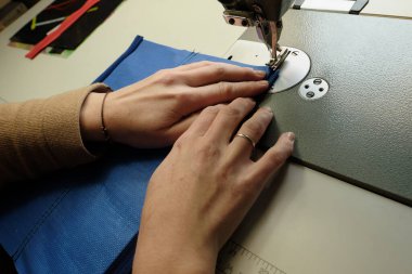 Dikiş makinesi kullanarak plastik bir kumaşa fermuar dikmek. Kadın eli, cetvel, aletler, bağlanma süreci. Bastırılmış ışık ve renk, yatay fotoğraf