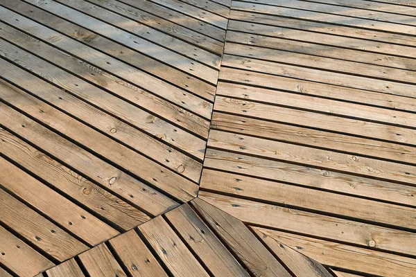 The sidewalk is made of smooth pine boards nailed to the joists with steel nails. An example of a walking path outdoors, in nature, harmoniously fits into the environment