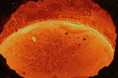 Parlak kırmızı bir tanktaki sıvı erimiş çelik, metalürjik bir fabrikadaki lavlara benzer, kalıplara dökülmeye hazır, yakın çekim, üst görünüm