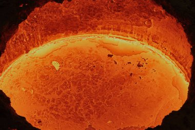 Parlak kırmızı bir tanktaki sıvı erimiş çelik, metalürjik bir fabrikadaki lavlara benzer, kalıplara dökülmeye hazır, yakın çekim, üst görünüm