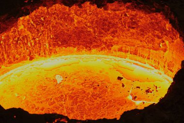 Parlak kırmızı bir tanktaki sıvı erimiş çelik, metalürjik bir fabrikadaki lavlara benzer, kalıplara dökülmeye hazır, yakın çekim, üst görünüm