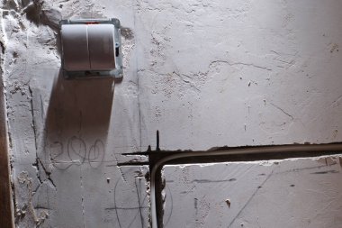 Öğütücü tarafından yapılmış bir oyukta bir dairenin beton duvarına elektrik kablosu döşeme örneği. Beyaz yalıtılmış bakır tel, alçıyla örülmeye hazır..