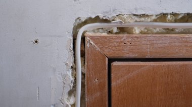 Öğütücü tarafından yapılmış bir oyukta bir dairenin beton duvarına elektrik kablosu döşeme örneği. Beyaz yalıtılmış bakır tel, alçıyla örülmeye hazır..