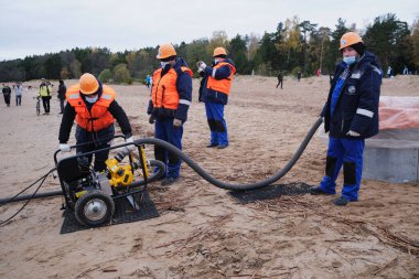 St. Petersburg, Rusya - 24 Ekim 2020: Finlandiya körfezinde sular çekildikten sonra temizlenen çevre hizmetleri çalışanları çöpleri, petrol sızıntılarını, mekanik yollarla zararlı maddeleri temizliyor