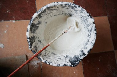 Mixer for building mixes in white liquid putty on the background of ready-made material for application to walls.