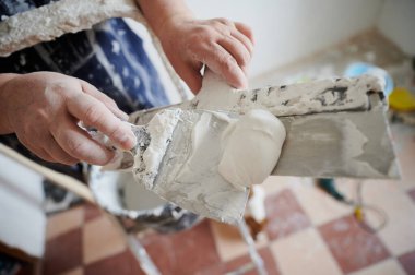 two spatulas with white putty, ready to be applied to the walls of the apartment. Home renovation by yourself.