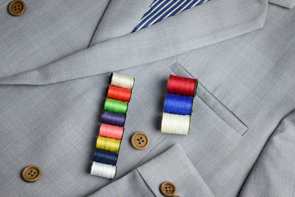 Small colorful thread coil on grey suit — Stock Photo, Image