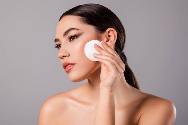 The image features a beautiful young woman demonstrating skincare routine by using a cotton pad for facial care, emphasizing beauty concepts.
