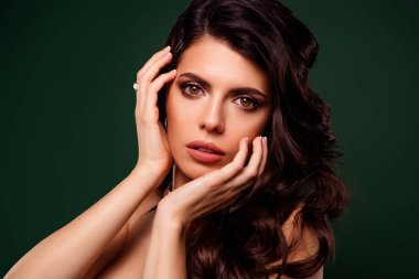 Beautiful young woman with luscious dark hair, highlighted by a glamourous makeup look. Captured against a green backdrop, radiating elegance and festive charm. Ideal for fashion, beauty, and celebration concepts.