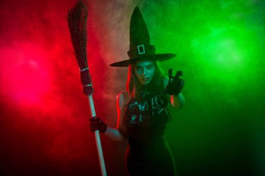 An enchanting woman dressed as a witch in a foggy ambiance conjuring spells. The captivating colors add mystery and holiday spirit.