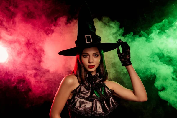 Cadılar Bayramı temalı, modaya uygun siyah cadı kostümlü, sisli, kırmızı ve yeşil arka planlı şık bir kadının portresi..