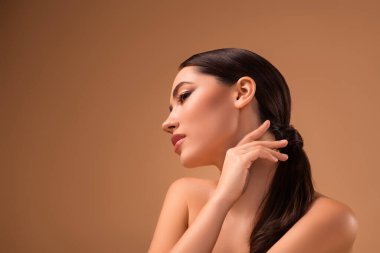 Sakin bir ortam tarafından kucaklanan genç bir kadının sanatsal tasviri. Saf cildini, zarif saç stilini ve rahatlatıcı bej bir arka planda zarif makyajını vurgulayarak güzelliği ve zarafeti ön plana çıkarıyor..