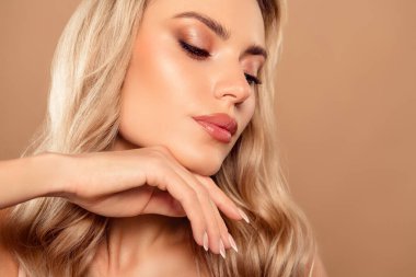 Kusursuz derisi ve zarif makyajı olan, tarafsız bir bej arka plana karşı güzelliği ve zarafeti vurgulayan büyüleyici bir genç kadın.