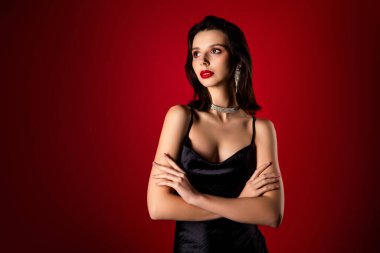 Zarif, siyah bir gece elbisesi içinde genç ve çekici bir manken, entelektüel, stil ve şehvetli bir güzelliği canlı kırmızı bir gradyan arka planına karşı sergiliyor..