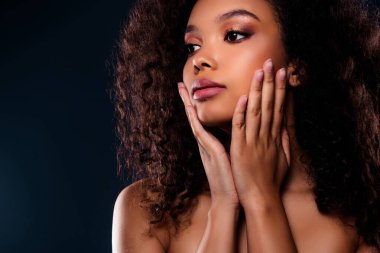 Kıvırcık saçlı, zarif makyajlı, stüdyo ortamında gösterişli bir güzellik ve zarafet sergileyen esmer bir kadının büyüleyici görüntüsü..