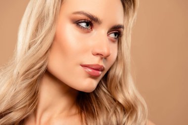 Pürüzsüz bir bej arka plan, çarpıcı cazibe ve entelektüelliğe sahip parlak ciltli, stil sahibi ve zarif makyajlı güzel bir genç kadının yakın çekimi..