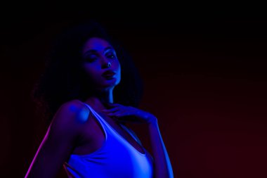 Canlı neon ışıklar altında, modern moda ve şehvetle gösterilen karizmatik genç bir kadının portresi. Büyüleyici atmosfer onun zarif stilini, özgüvenini ve fotoğrafın sanatsal doğasını vurguluyor..