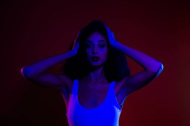 Neon ışığın altında büyüleyici renklerle poz veren zarif, genç bir kadın. Şık, modaya uygun bir duruş, gösterişli bir güzellik ve modern cazibe..