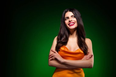 Göz kamaştırıcı saten elbisesi içinde genç ve güzel bir kadın canlı bir arka plana karşı güven verici bir şekilde poz veriyor, dikkat çekici bir şekilde kendine güven, zarafet ve güzellik saçıyor.