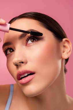 Kirpiklerini rimelle parlatan, zarif bir makyaj, pürüzsüz bir ten ve canlı pembe bir arka plana karşı şık bir hava veren bir kadının yakın plan çekimi..