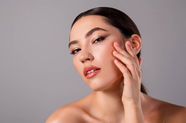 Kusursuz bir cildi, zarif bir makyajı ve zarif bir duruşu olan, güzellik, tarz ve cilt bakımını vurgulayan genç bir kadın modelin yakın çekimi..