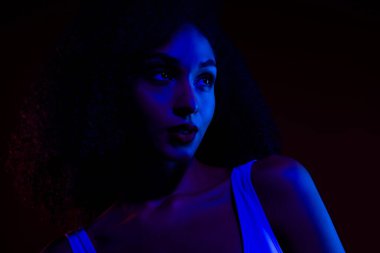 Canlı mavi ve kırmızı neon ışıklarla aydınlatılmış genç bir kadının sanatsal portresi güzellik, cazibe ve modern estetik üzerine odaklanmış şık ve büyüleyici bir etki yaratıyor..
