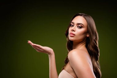 Zarif makyaj, gür esmer saç ve kendine güvenen bir ifade ile zarif bir şekilde poz veren entelektüel ve şık genç bir kadın, gradyan yeşil bir zemin, zarafet ve cazibe yayıyor..