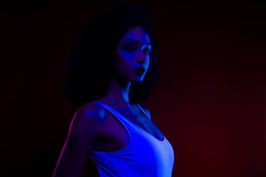 Çarpıcı mavi ve kırmızı neon ışıklarla aydınlatılmış genç bir kadın atmosferik bir ortamda güzellik, moda ve çağdaş sanatı vurguluyor..