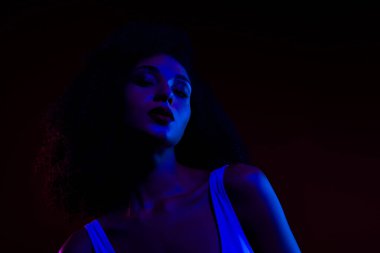 Büyüleyici bir görüntü canlı mavi ve kırmızı neon ışıklar altında zarif ve çağdaş sanatla harmanlanmış genç bir kadını gösteriyor..