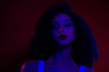 Canlı neon ve kırmızı ışıklarla aydınlatılmış genç bir kadın yaratıcı ve modern bir şekilde tasvir edilmiş karizma ve zarafet yayar..