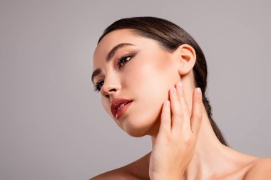 Kusursuz makyaj ve parlak cilt sergileyen esmer bir kadının yakın çekimi. Görüntü güzellik, zarafet ve kozmetik sanatına odaklanıyor..