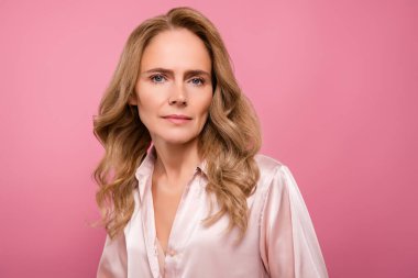 Zarif orta yaşlı kadın pembe bir zemine poz veriyor doğal güzelliğini, şık saçlarını ve kadınsı soğukkanlılığını vurguluyor..