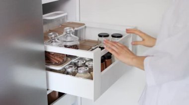 Kadın eli, çekmeceyi baharatlarla kapatıyor. Mutfakta baharat depoluyor. Ev rutini. 4k görüntü