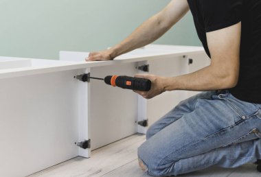 Genç bir zanaatkar mobilya montajı yapıyor. Teyidi yakın plan çekiyoruz. Profesyonel mobilya montajı. Yeni mobilya montajı. Mobilya kurulumu.