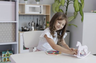 Küçük kız çocuk odasındaki masada masa eğitimi üzerine oyun oynuyordu. Çocuk gelişimi kavramı. Çocuklar için boş zaman kavramı..