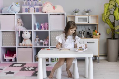 Küçük kız çocuk odasındaki masada masa eğitimi üzerine oyun oynuyordu. Çocuk gelişimi kavramı. Çocuklar için boş zaman kavramı..