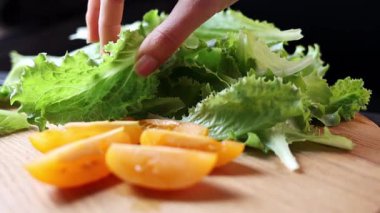 Domateslerin ve marulların yakın plan çekimleri. Siyah arka planda tahta bir tahta üzerinde. Sağlıklı beslenme ve organik tarım ürünleri kavramı. Yavaş çekim.