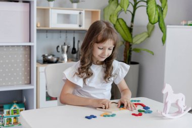 Küçük kız çocuk odasındaki masada masa eğitimi üzerine oyun oynuyordu. Çocuk gelişimi kavramı. Çocuklar için boş zaman kavramı..