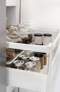 Mutfak çekmecesinde duran baharat kavanozlarının yakın çekimi. Mutfakta baharat depoluyor. Ev rutini. Dikey fotoğraf.