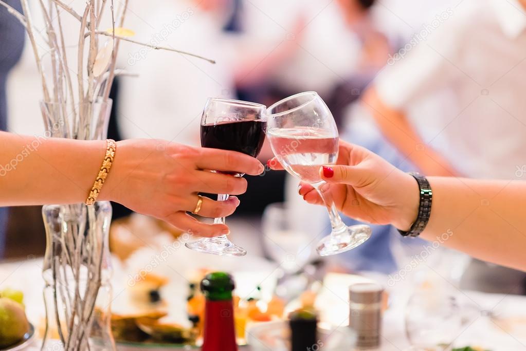 female hands with two wine glasses clink