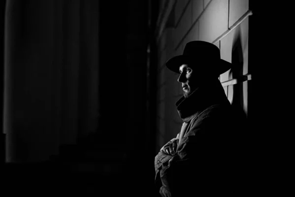 Ciemna sylwetka mężczyzny w płaszczu przeciwdeszczowym z kapeluszem i blizną na twarzy w nocy — Zdjęcie stockowe