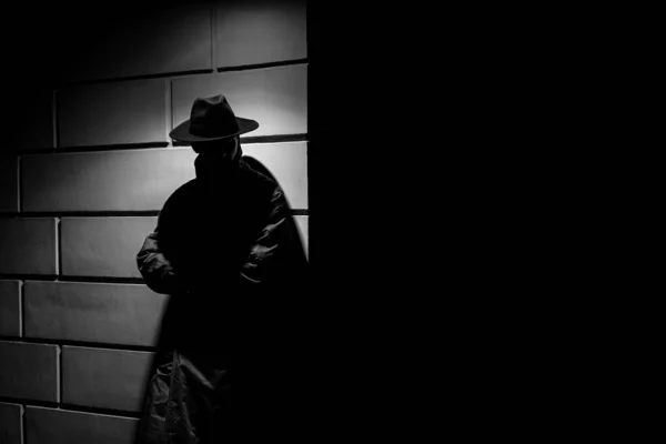 Silhouette sombre d'un homme en imperméable avec un chapeau la nuit — Photo