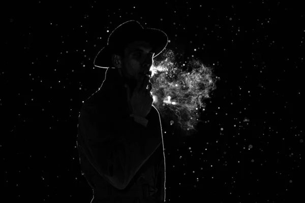 Mörk siluett av en man i hatt Röka en cigarett i regnet — Stockfoto