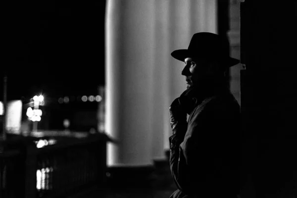 Silhouette sombre d'un homme en imperméable avec un chapeau et une cicatrice sur le visage la nuit — Photo