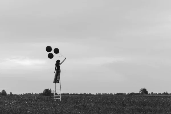 Surrealistische foto van een eenzaam meisje op de trap met ballonnen — Stockfoto