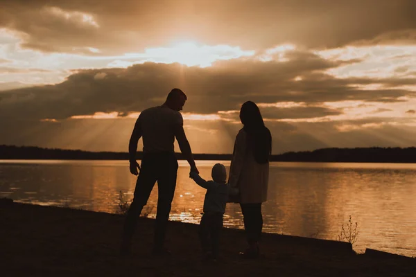 Silhouette of a family with their son on the beach in summer — Stock Photo, Image